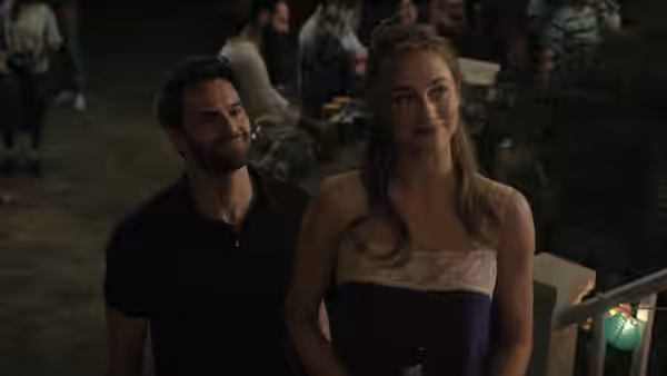 Olive Smith (Lili Reinhart) stands at an outdoor gathering as Dr. Adam Carlsen (Tom Bateman) looks at her