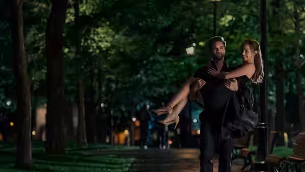 Dr. Adam Carlsen (Tom Bateman) carries Olive Smith (Lili Reinhart) through a tree-lined park