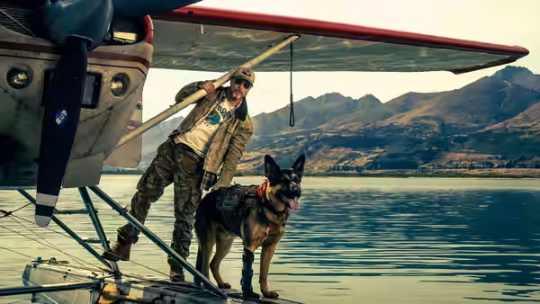 James Belmont (Brad Pitt) standing with a dog on a seaplane pontoon over water