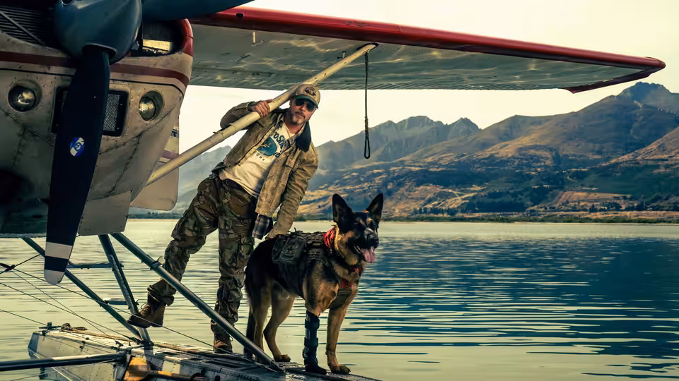 James Belmont (Brad Pitt) standing with a dog on a seaplane pontoon over water