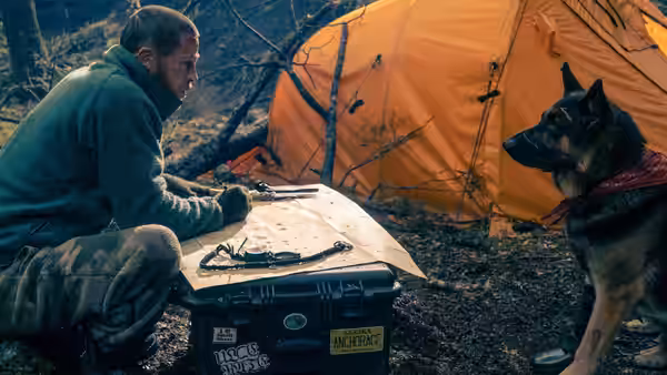 James Belmont (Brad Pitt) kneeling by a case with his dog near an orange tent