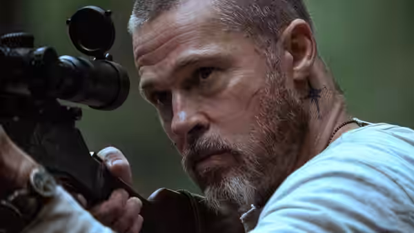 James Belmont (Brad Pitt) aims a scoped rifle from a low position