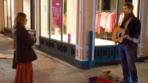 Guy (Glen Hansard) with guitar speaking to Girl (Markéta Irglová) outside a shop