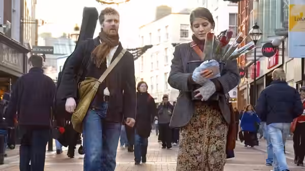 Guy (Glen Hansard) carrying a guitar case beside Girl (Markéta Irglová) holding flowers