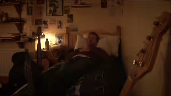 Guy (Glen Hansard) asleep in bed with a guitar beside him