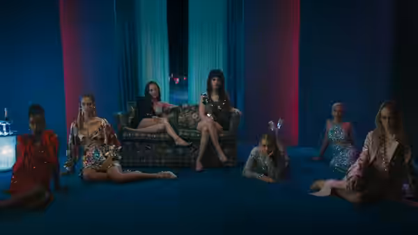 Women in sequined dresses lounging on the floor of a blue room