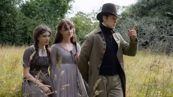Elinor Dashwood (Daisy Edgar-Jones) and Marianne Dashwood (Esmé Creed-Miles) walk through a meadow with a top-hatted man