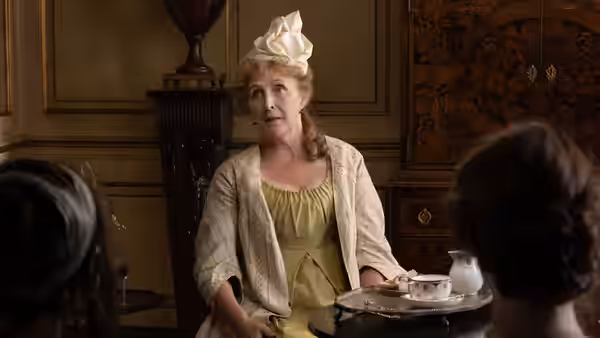 Mrs. Jennings (Fiona Shaw) sits with a tea tray before two women
