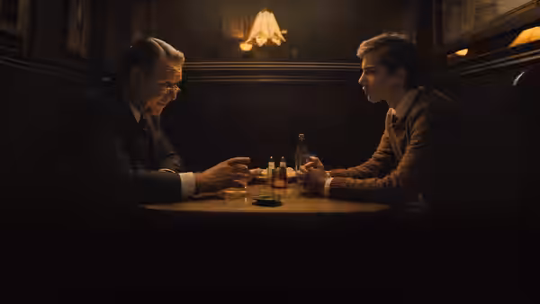 Henry Murray (Russell Crowe) talks with a younger man over drinks at a wooden table