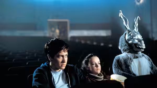 Donnie Darko (Jake Gyllenhaal) and Gretchen Ross (Jena Malone) sit beside Frank in a theater