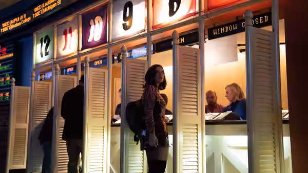 Julia (Julia Fox) standing at the betting windows inside a gambling hall