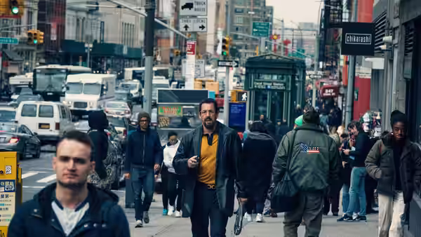 Howard Ratner (Adam Sandler) walking on a crowded New York City street