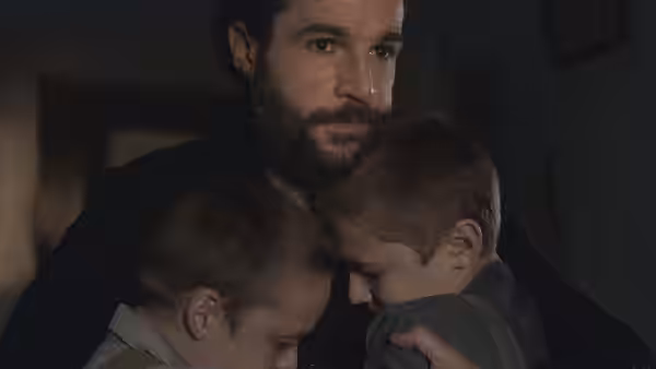 Adam Trask (Christopher Abbott) embracing his two young sons in a dim room