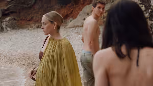 Anne (Chloë Sevigny) on a pebble beach with a shirtless man nearby