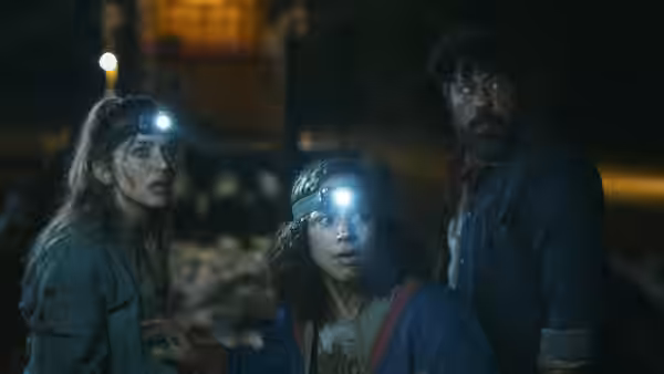 Three explorers wearing headlamps look around a dark interior