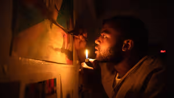 A man uses a lighter to illuminate a painting as he works on it