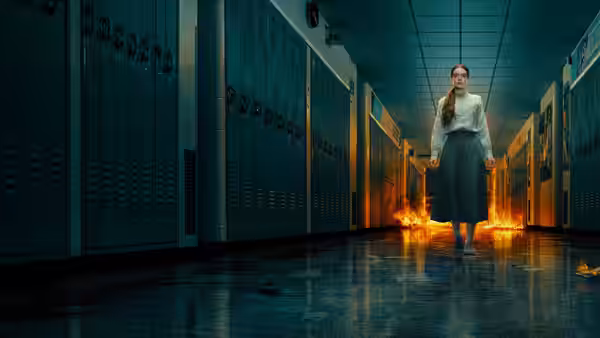 Carrie White (Summer H. Howell) walks down a school hallway as flames spread behind her