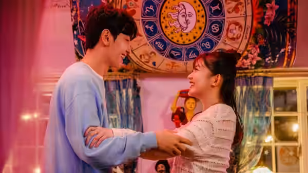 Lee Yu-bin (Ji Chang-wook) and Shirahama Karin (Mio Imada) hold hands beneath a colorful zodiac tapestry