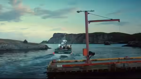 Fishing boat approaching a wooden dock with crane on calm water at dusk
