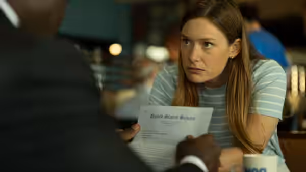 Rachel Keller as Olivia Siffre reviewing papers across from a suited man in an office