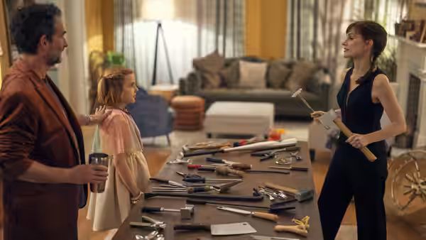 Russell Martin and Bela watch as Ursula holds a tool across a table of scattered tools