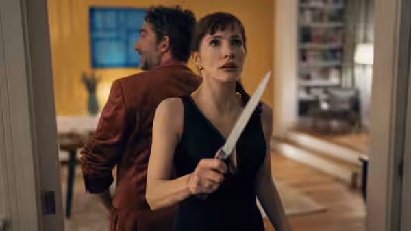 Ursula (Jessica Chastain) grips a kitchen knife as a man turns away in the house