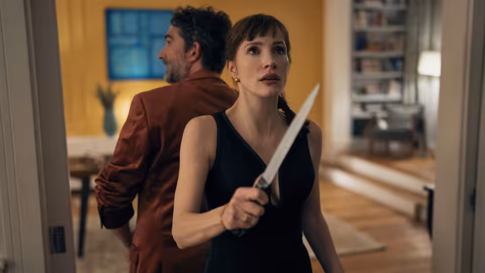 Ursula (Jessica Chastain) grips a kitchen knife as a man turns away in the house
