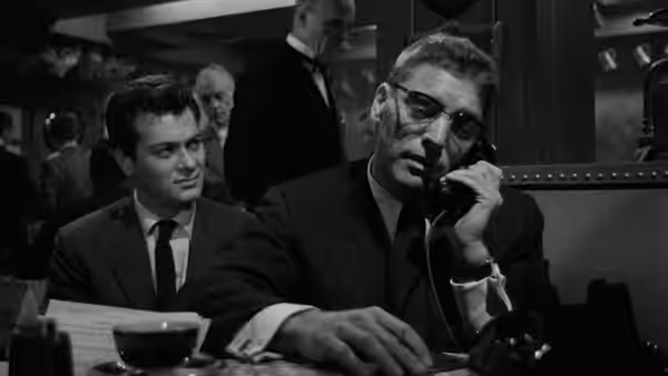 J.J. Hunsecker (Burt Lancaster) talks on the phone as Sidney Falco (Tony Curtis) sits beside him