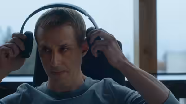 A man adjusts large headphones while seated in a bright office chair