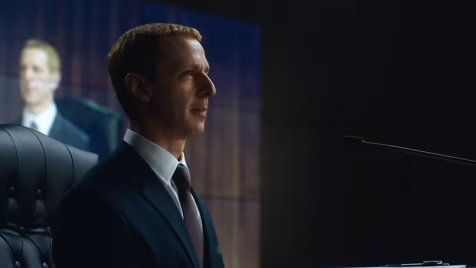 Mark Zuckerberg (Jeremy Strong) faces a presentation screen in a dim conference room