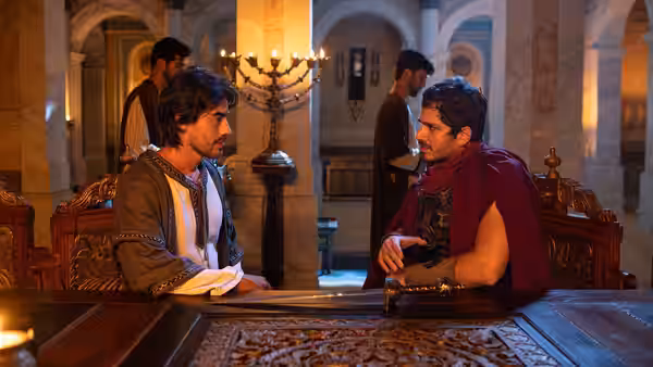 Judá Ben-Hur (Vinícius Redd) and Messala (Rômulo Weber) seated at a table in a marble hall