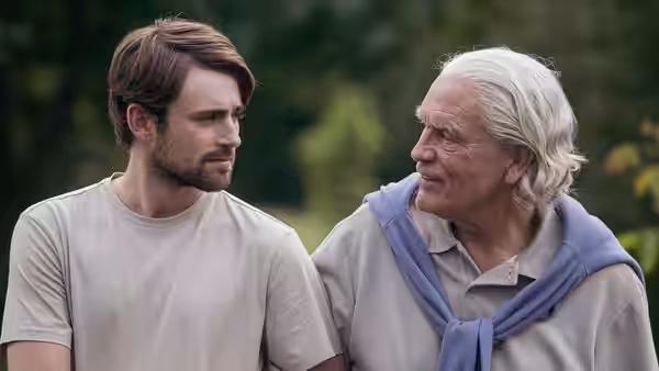 a young man and older man talking together outdoors in daylight