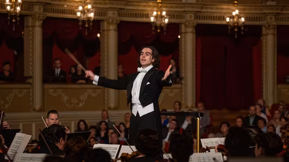 Sergiu Celibidache (Ben Schnetzer) conducts an orchestra before an audience in a concert hall