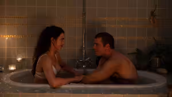 A woman and a man holding hands while sitting in a bathtub