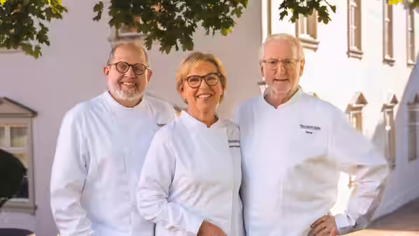 Wenche Andersen stands between two chefs outside the school, with Eyvind Hellstrøm on the right