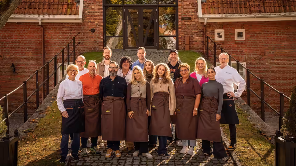 A group of cooks and teachers gathers outside a brick school building