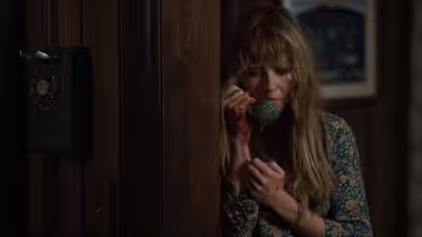 Pamela Voorhees (Linda Cardellini) holds a telephone, blood on her hand, beside a wooden wall