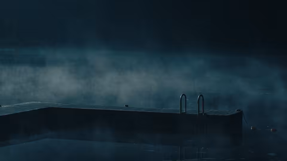 A misty dock extends over a dark lake at night