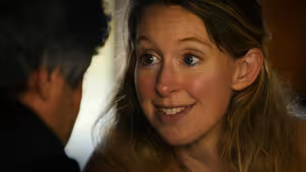 Woman with long hair smiles while looking toward a man in close-up
