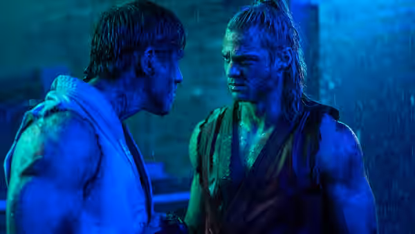 Two fighters facing each other under blue light in heavy rain