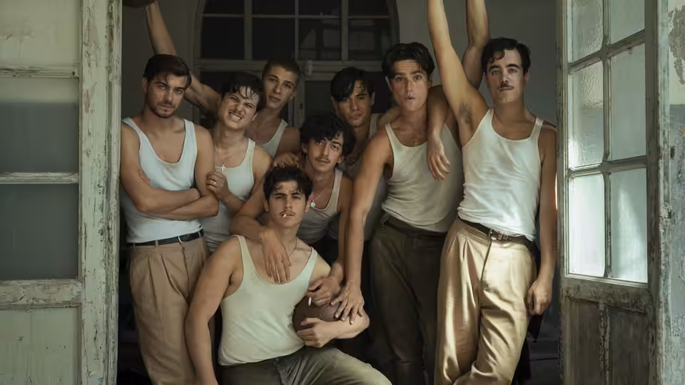 Group of young men in tank tops posing together in a doorway