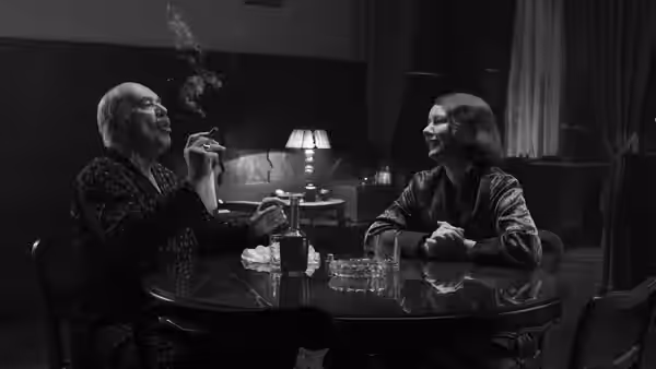 Thomas Mann (Hanns Zischler) smoking at a table with another man