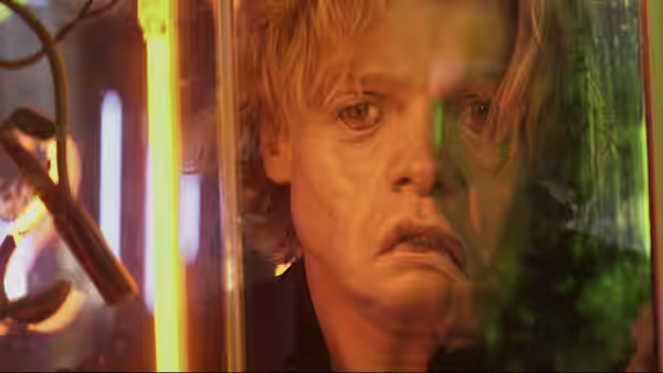 Matt Hagen (Tom Rhys Harries) looks through glass amid glowing laboratory equipment