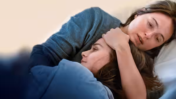 Nora Borg (Renate Reinsve) comforting a younger woman lying in bed