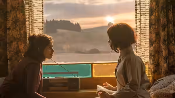 Klara (Jenna Ortega) sitting with another woman by a sunlit window