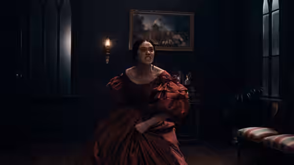 a woman in a red dress seated on the floor in a dark room