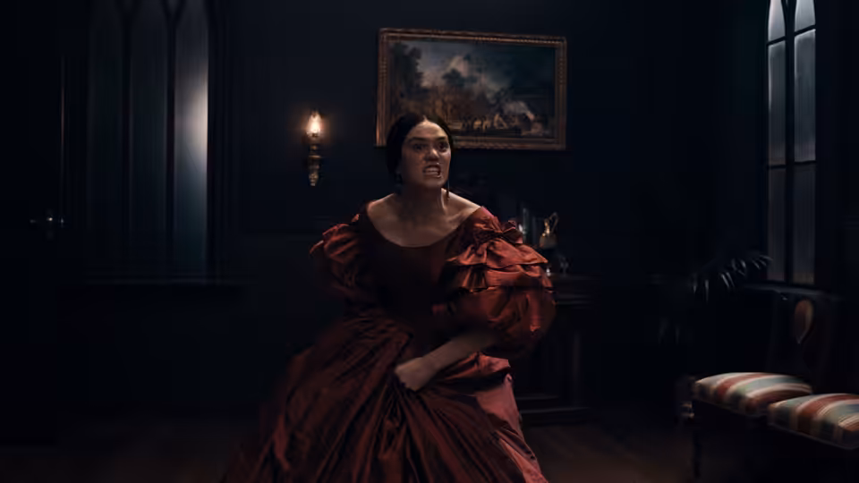 a woman in a red dress seated on the floor in a dark room