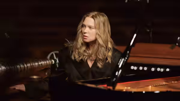 Lucy Weiss (Léa Seydoux) seated at a grand piano in dim light