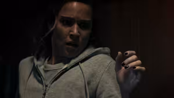 A woman in a grey hoodie recoils with a startled expression