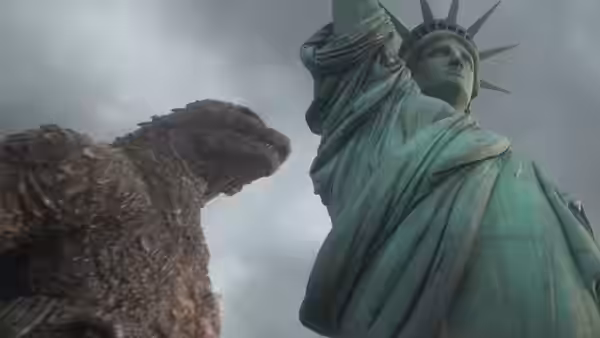 Godzilla faces the Statue of Liberty beneath an overcast sky